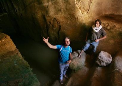 British Archaelogist Shimon Gibson left, gestures as site manager Rafi Lewis places his foot in a ceremonial stone as they stand in the water of a large cistern in the cave the excavation team believes John the Baptizer anointed many of his students. August 16, 2004