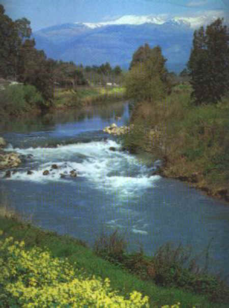 River Jordan with snowclad Mount Hermon in the background - Northern Israel near Galilee and Golan Heights